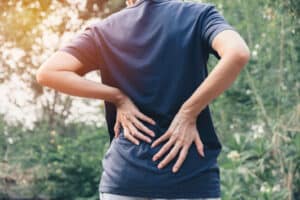 A close-up shot of a woman holding her lower back, struggling with lower back pain