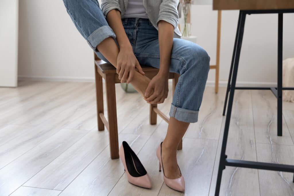 Woman sitting down and massaging feet after day of wearing heels